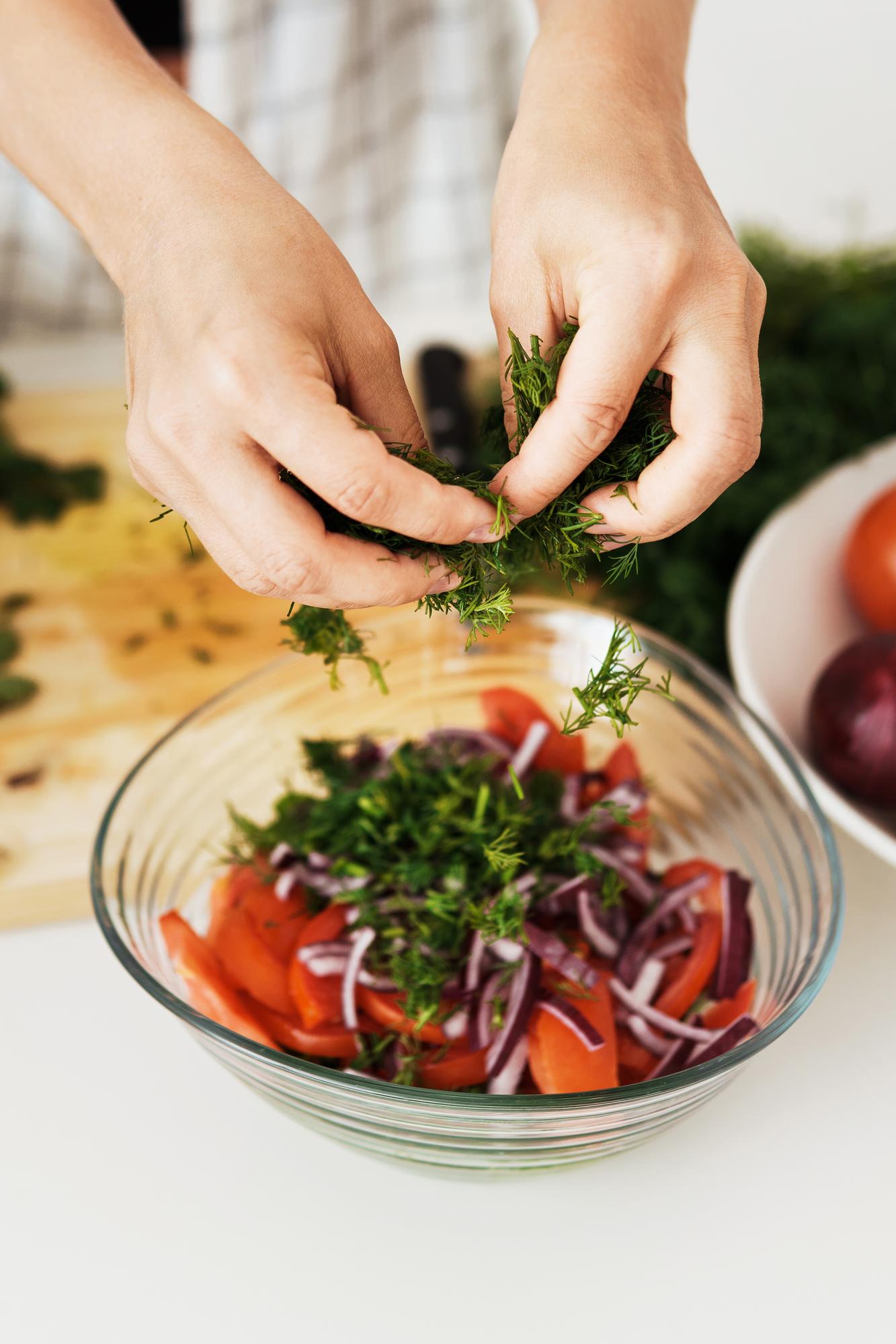 closeup hands garnishing salad